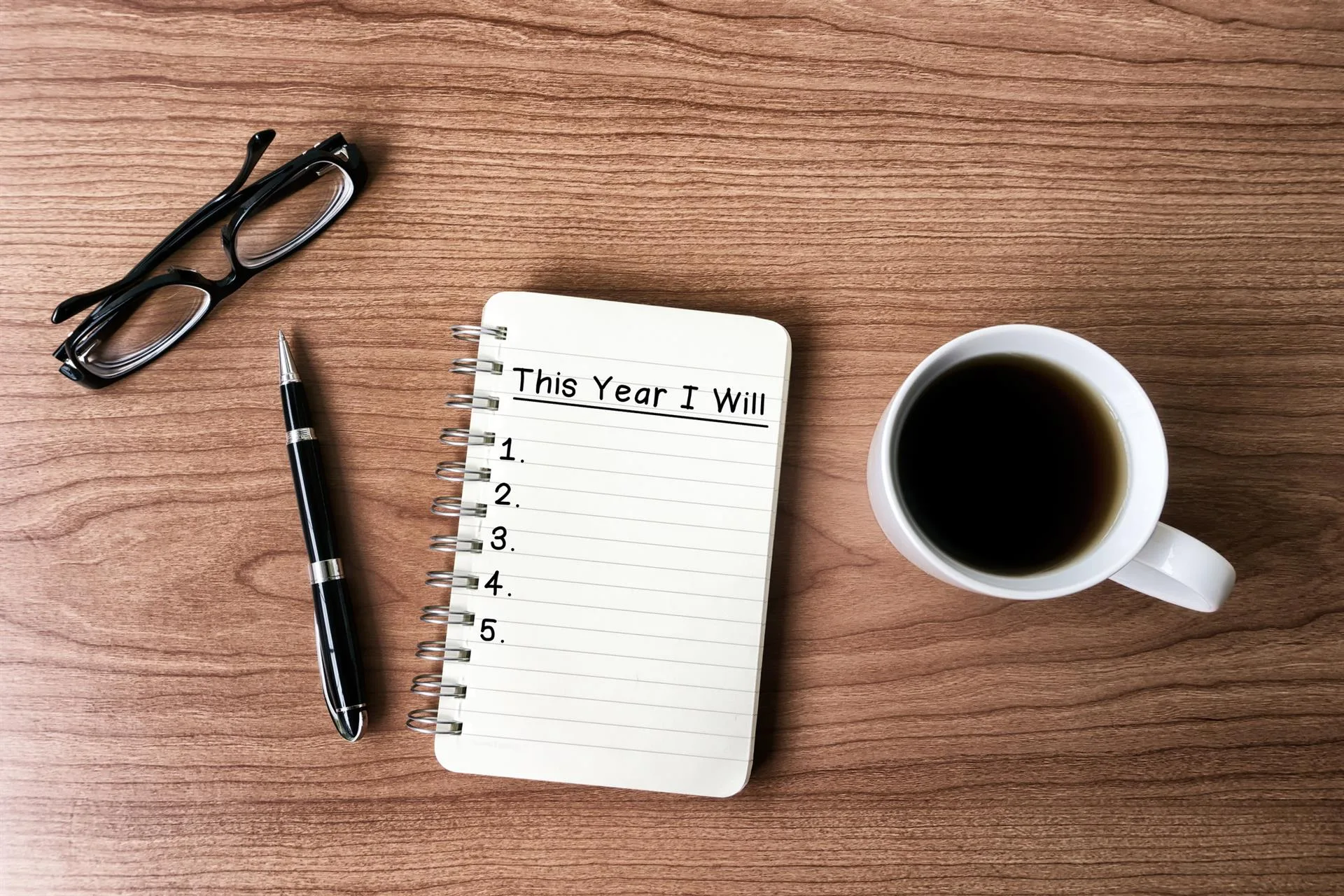 glasses, pen, notebook, and coffee "this year I will"