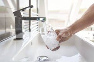 Filling up a glass with clean drinking water from bathroom faucet